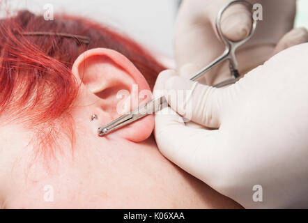Professional posizionando il gioiello di perforazione sull'orecchio con sfera. Tragus tipo Foto Stock
