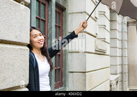 Allegro ragazza asiatica con ombrello in un giorno di pioggia Foto Stock