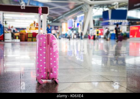 Valigia rosa su una stazione ferroviaria trafficata Foto Stock