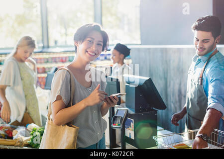 Ritratto sorridente giovane donna alla drogheria checkout Foto Stock