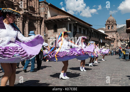 Una troupe di danza vorticosamente lungo una strada di ciottoli nel centro storico di Cusco durante i tradizionali festeggiamenti del Corpus Christi, Perù. Foto Stock