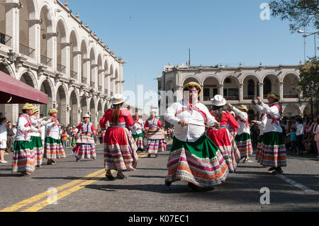 Un gruppo di agricoltori vestiti in abiti tradizionali danze lungo una strada di ciottoli vicino a Plaza de Armas, Arequipa, Perù. Foto Stock