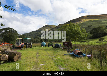 Trattori agricoli ed altre apparecchiature a Hudson Place, Loweswater, Lake District, Cumbria, Inghilterra. Burnbank cadde e Carling Knott sono anche mostrati. Foto Stock