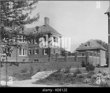 Vista parziale di un mattone mansion vicino a Roland Park e Guilford, la maggior parte delle finestre sono di colore scuro persiane e vi è un grande recinto di mattoni che circonda una parte dell'albergo, vi è anche un distinto e più piccolo edificio in mattoni sulla proprietà, Stati Uniti, 1910. Questa immagine viene da una serie di documentare la costruzione e la vendita di case nel parco di Roland/Guilford quartiere di Baltimora, un tram sobborgo e una delle prime comunità prevista negli Stati Uniti. Foto Stock