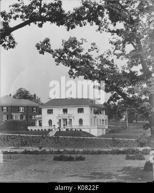 Fotografia di una Roland Park Home a Baltimora, un bianco a due piani casa su una collina erbosa con un grande portico anteriore e una facciata ornata, oltre ad una casa di mattoni di pari statura, Stati Uniti, 1920. Questa immagine viene da una serie di documentare la costruzione e la vendita di case nel parco di Roland/Guilford quartiere di Baltimora, un tram sobborgo e una delle prime comunità prevista negli Stati Uniti. Foto Stock