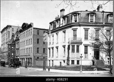 Una strada a Baltimore con un marciapiede e diversi edifici di grandi dimensioni, incluso un mattone garage parcheggio etichettato 'Vermont Garage, ' che diverse vetture stanno entrando; un grande edificio residenziale, eventualmente un appartamento edificio, con una serie di gradini che conducono alla porta anteriore, prima storia di finestre a baia, una piccola seconda storia di balcone, top story finestre dormer e vari camini; a Baltimora, Maryland, Vermont, 1910. Questa immagine viene da una serie di documentare la costruzione e la vendita di case nel parco di Roland/Guilford quartiere di Baltimora, un tram sobborgo e una delle prime comunità pianificata Foto Stock