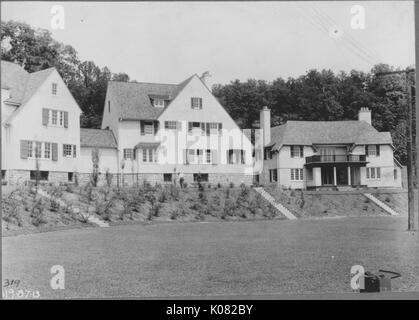 Facciata di due case su una lieve collina con piccoli alberi, casa sulla destra è anteriore e seconda storia di portici con colonne, campo di erba nella parte anteriore del case, telefono bianchi nella parte anteriore del case, Baltimore, Maryland, 1910. Questa immagine viene da una serie di documentare la costruzione e la vendita di case nel parco di Roland/Guilford quartiere di Baltimora, un tram sobborgo e una delle prime comunità prevista negli Stati Uniti. Foto Stock