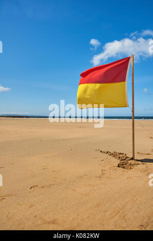 Rosso e giallo bandiera di avvertimento contro un cielo blu di consigliare i bagnanti sulla spiaggia di Ballybunion, nella contea di Kerry Irlanda Foto Stock