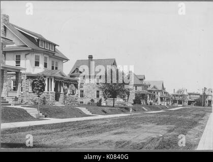 Numerose case fodera una tranquilla strada residenziale a Baltimora, Maryland, con un marciapiede che corre parallelo alla strada, ogni casa almeno parzialmente di pietra, ciascuna dotata di un portico anteriore, abbaini, un caminetto e un piccolo set di scale che conducono al proprio cantiere, Baltimore, Maryland, 1910. Questa immagine viene da una serie di documentare la costruzione e la vendita di case nel parco di Roland/Guilford quartiere di Baltimora, un tram sobborgo e una delle prime comunità prevista negli Stati Uniti. Foto Stock