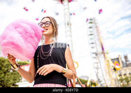 Donna con cotone candy presso il parco di divertimenti Foto Stock