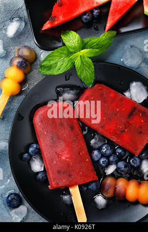 Frutto di ghiaccio da cocomero, arancione e mirtilli con foglie di menta. Vista superiore del dessert estivo Foto Stock