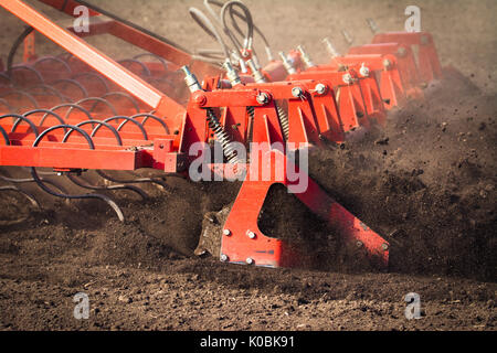 L'agricoltore nel trattore la preparazione di terra con il coltivatore del letto di semina in primavera Foto Stock