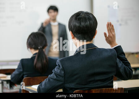 Maestro di denominazione di un allievo alzando la mano in classe Foto Stock