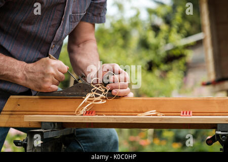 Uomo con le mani del falegname piano su sfondo di legno Foto Stock