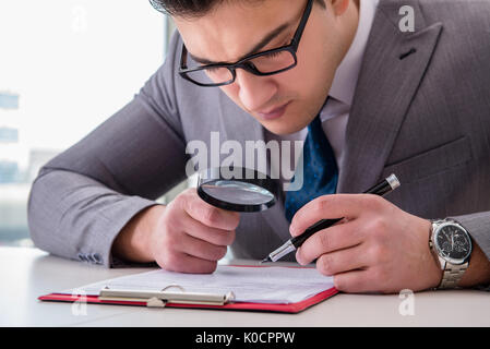 Imprenditore con lente di ingrandimento studiando accordo Foto Stock