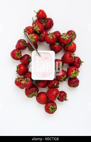 Contenitore con yogurt e un mucchio di fragole fresche su sfondo bianco, isolata, vista dall'alto. Foto Stock