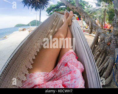 Le gambe della donna nella rilassante amaca su una spiaggia tropicale Foto Stock