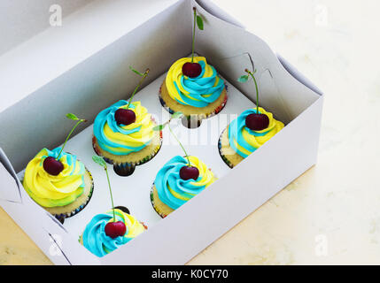 Tortini di vaniglia con un tappo colorato di crema in una finestra su sfondo chiaro Foto Stock