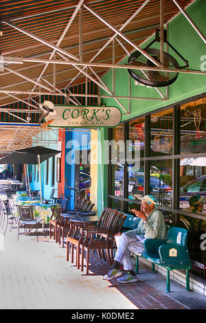 Il vecchio uomo seduto di fumare un sigaro al di fuori del sughero Cigar Bar nella vecchia strada principale di Bradenton, FL, Stati Uniti d'America Foto Stock