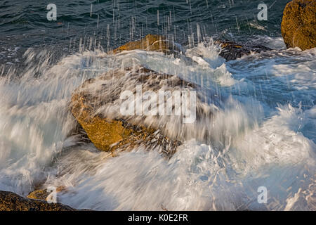 Una lunga esposizione giorno seascape con slow shutter e acqua che fluisce oltre le pietre Foto Stock