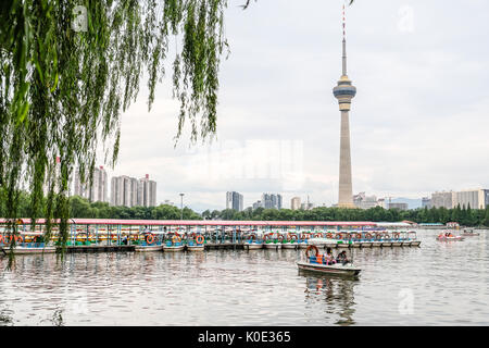 Persone in barca di pedalata a Yu Yuan Tan park con torre di TVCC in background Foto Stock