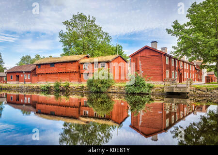 Il vecchio tradizionale rosso svedese case in legno che riflette nel fiume Svartan Wadkoping nel quartiere storico in Orebro, Svezia Foto Stock