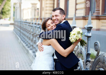 Felice sposa e lo sposo ridere abbracciando sorridente sul giorno di nozze Foto Stock