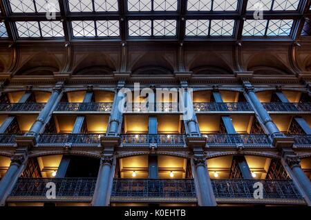 Un'immagine a basso angolo dei livelli della George Peabody Library, una biblioteca di ricerca per la Johns Hopkins University, con ringhiere in ghisa e lampade luminose esposte che illuminano le librerie complete durante il Baltimore Book Festival, Baltimora, Maryland, 28 settembre 2013. Cortesia Eric Chen. Foto Stock