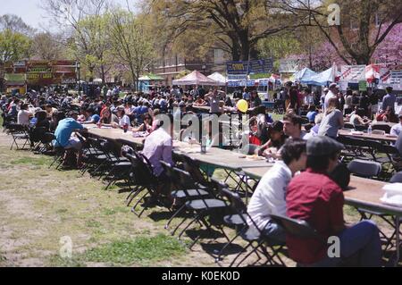 Gli studenti universitari e i membri della Johns Hopkins e baltimore europee sedere ai tavoli, mangiare e socializzare come cibo sta li circondano, durante la fiera di primavera, un festival annuale di musica, cibo, negozi, e più che si svolge ogni anno in primavera su homewood campus della Johns Hopkins University di Baltimora, Maryland. 2014. cortesia eric chen. Foto Stock