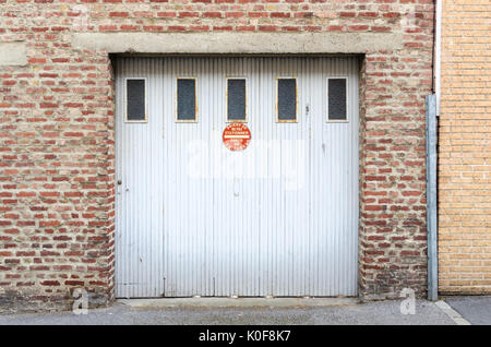 Vecchio bianco porta di garage con segno dicendo no parcheggio in francese di Saint-omer, nel nord est della Francia Foto Stock