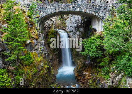 Christine cade incorniciato dalle macerie arcata in pietra ponte di Paradise Road, il Parco Nazionale del Monte Rainier, la cascata di gamma, Washington, Stati Uniti d'America. Foto Stock