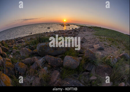 Tramonto sulla spiaggia rocciosa, pacifico mare, cielo arancione. kihnu, piccola isola in Estonia. mar baltico, l'Europa. ambiente naturale dello sfondo. Foto Stock
