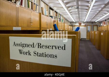 Assegnate stazioni di lavoro, con uno studente che alza le mani sopra il cubicolo, nella biblioteca Milton S. Eisenhower nel campus Homewood della Johns Hopkins University a Baltimora, Maryland, 2015. Cortesia Eric Chen. Foto Stock