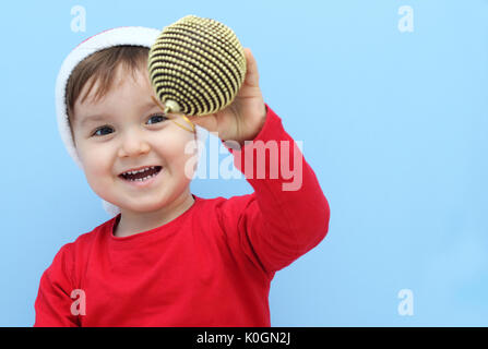 Felice piccolo bambino che mostra un ornamento di Natale Foto Stock