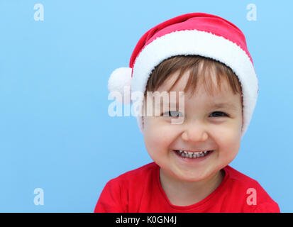 Felice piccolo bambino vestito con una Santa Claus costume in uno sfondo blu Foto Stock