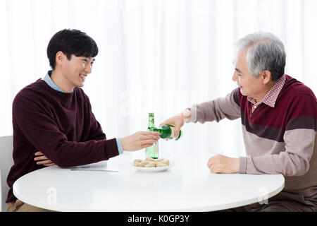 Sorridente uomo senior e il suo giovane figlio di bere Foto Stock