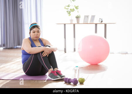 Giovane donna grassa stanco seduto durante l'esercizio Foto Stock