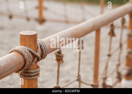 Una staccionata in legno con corda in un parco giochi Foto Stock