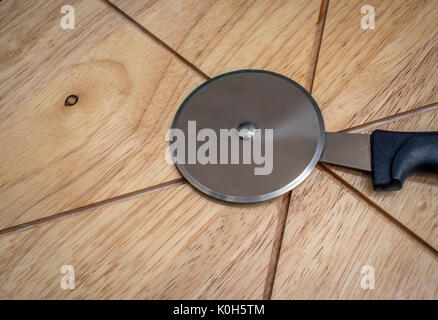 Tagliapizza rullo coltello sulla parte superiore di una pizza tagliere Foto Stock