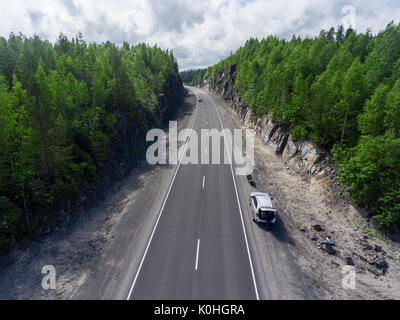 Di automobili e moto permanente sulla strada del paese due corsie tra rocce, vista aerea Foto Stock