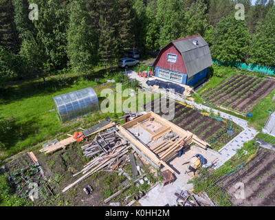 Vista superiore a homestead con casa in legno, serre e giardino. Uomo maturo edificio bathhouse. La Russia Foto Stock