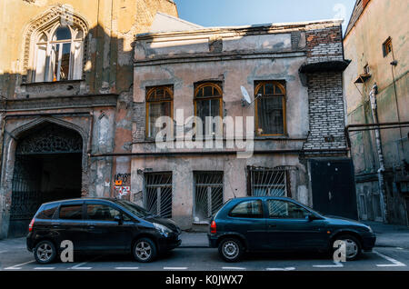 Tbilisi, Georgia - 15 Ottobre 2016: sgangherate architettura antica nel centro di Tbilisi sullo sfondo delle automobili parcheggiate lungo la strada, Georgia. Foto Stock