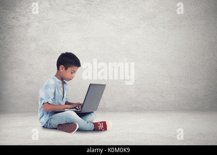 Felice ragazzo seduto al piano con il computer portatile Foto Stock