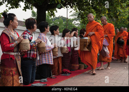 Lo zafferano monaci vestiti di camminare lungo la strada principale di Luang Prabang, Laos, durante l elemosina dando cerimonia. Con oltre 30 monasteri raggruppati nella compa Foto Stock
