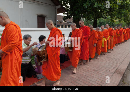 Una processione di monaci scalzi raccoglie elemosina lungo le strade di Luang Prabang, Laos. La più comune doni offerti sono di riso appiccicoso, banane, dolce Foto Stock