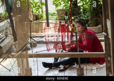 Una donna da Xhang Khong villaggio nei pressi di Luang Prabang aziona una ruota di filatura per rendere filati di seta, che saranno utilizzati per la tessitura tradizionale Lao tessili. Foto Stock