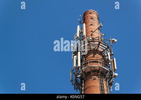 Antenne per telecomunicazioni su una vecchia ciminiera in mattoni. Concetto industriale. La tecnologia moderna Foto Stock