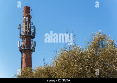 Antenne per telecomunicazioni su una vecchia ciminiera in mattoni. Concetto industriale. La tecnologia moderna Foto Stock