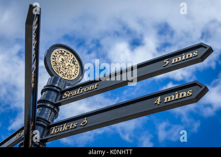 Un segno di ornati in Suffolk cittadina balneare di Southwold punti il modo per lui il lungomare. Foto Stock