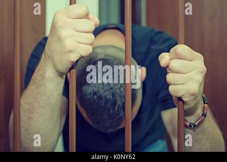Abstract. Le mani del prigioniero su un traliccio di acciaio vicino. Il carcere, uomo in manette. Assassin, un assassino dietro le sbarre. Foto Stock